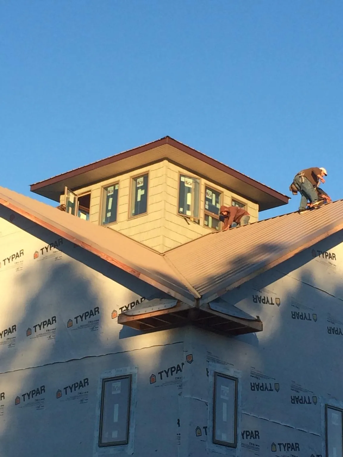 Roofers working around a rooftop cupola on a new metal roof at sunset — Roof Waterproofing in San Marcos by Roofing Brothers